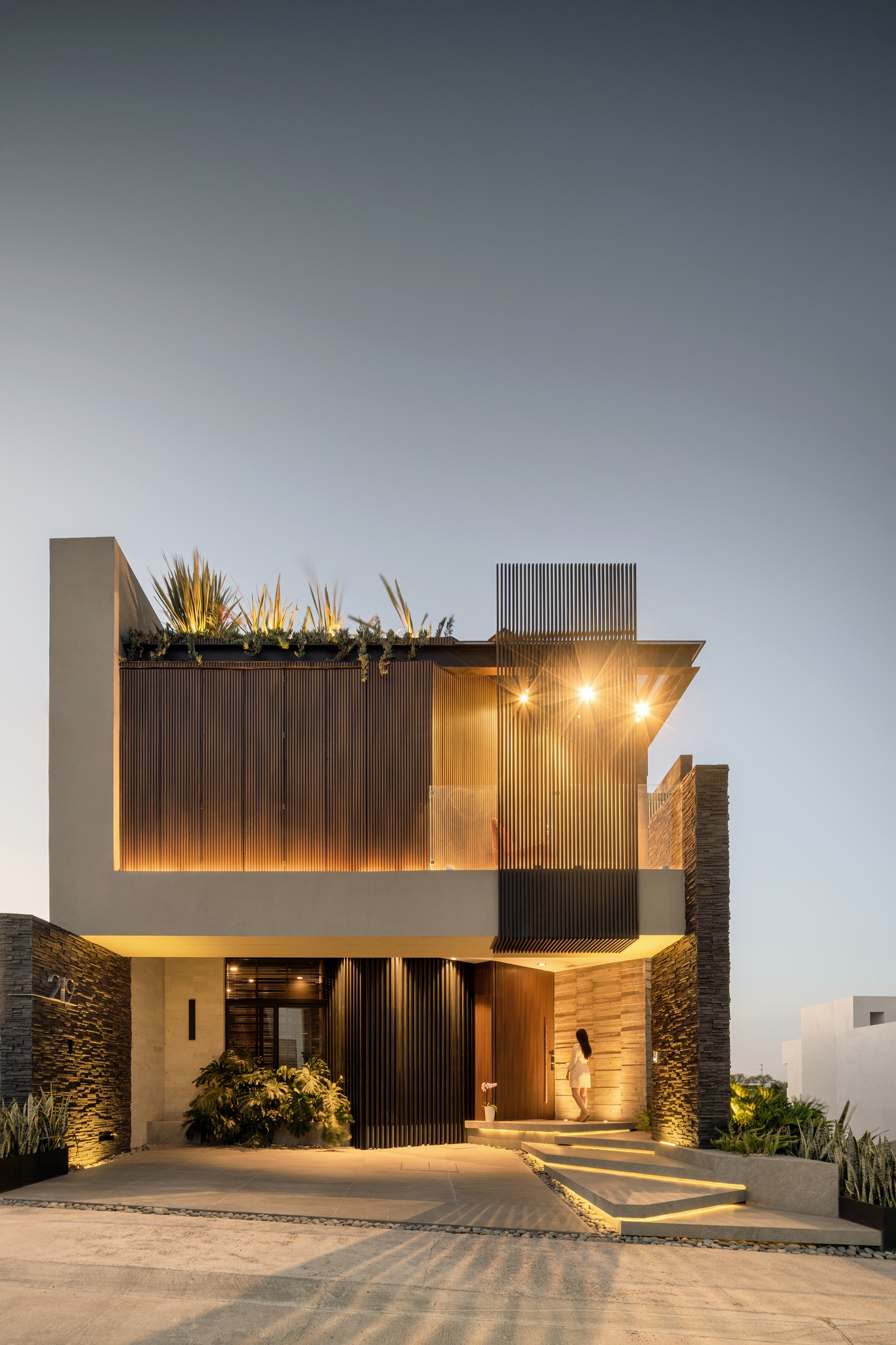 Fachada con celosías de madera e iluminación cálida